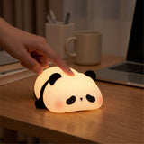 Panda-shaped USB rechargeable night light glowing softly on a wooden bedside table